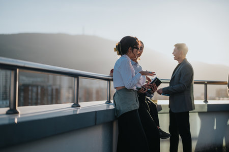 Diverse colleagues brainstorming on a high-rise balcony at sunsetの写真素材