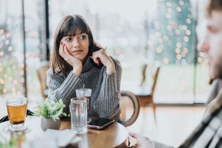 Woman in a cafe looking thoughtful during conversation with warm lightingの写真素材