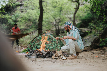 Camping scene featuring two individuals preparing a campfire in a forest settingの写真素材