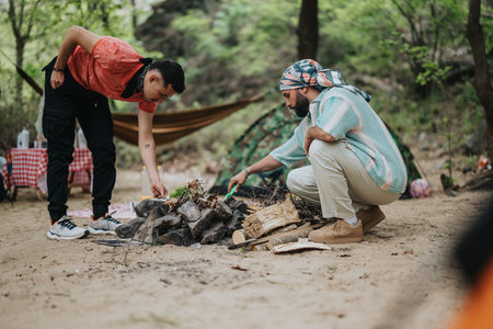 Friends preparing a campfire together at a forest campsite during daytimeの写真素材