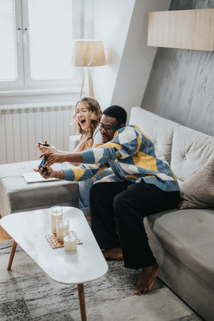 Happy couple enjoying video games together inside a stylish living roomの写真素材
