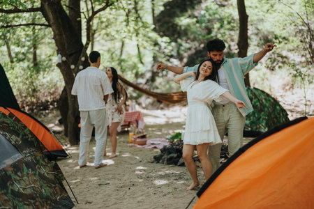 Friends enjoying dance and relaxation moments while camping in a forest settingの写真素材
