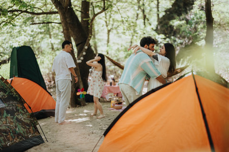 Group camping trip with tents in a lush green forest settingの写真素材
