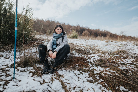 Young woman resting during a winter hike in a snowy fieldの写真素材