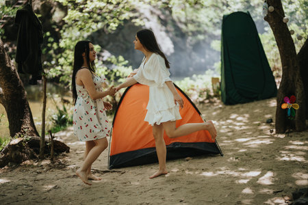 Two friends enjoying a summer day camping in a scenic forest areaの写真素材
