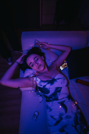 Woman Relaxing on a Couch With Fairy Lights During a Partyの写真素材