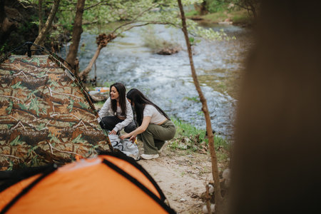 Two friends enjoying a camping trip by a riverside campsiteの写真素材