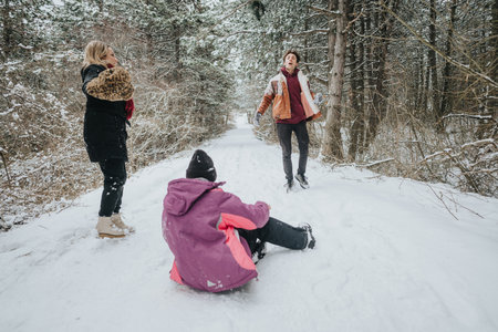 Friends enjoying playful moments in a snowy forest during winterの写真素材