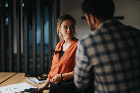 Two professionals engaged in discussion at modern office workspaceの写真素材