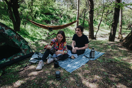Young couple camping and relaxing outdoors in a green forested areaの写真素材