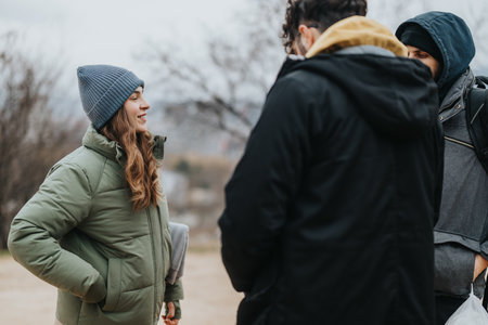 Young friends enjoying a conversation outdoors during a chilly winter dayの写真素材