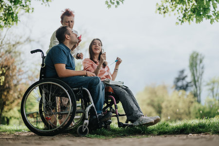 A cheerful group enjoying a sunny day outdoors, featuring two individuals in wheelchairs and one sharing a joyful moment together.の写真素材