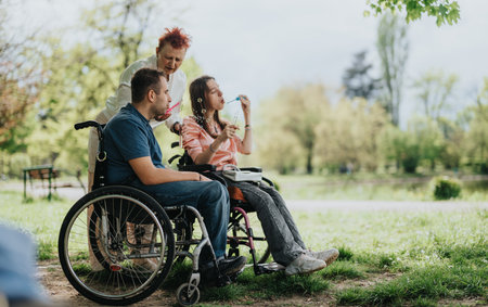 Outdoor gathering of people in wheelchairs enjoying nature and blowing bubbles on a sunny dayの写真素材