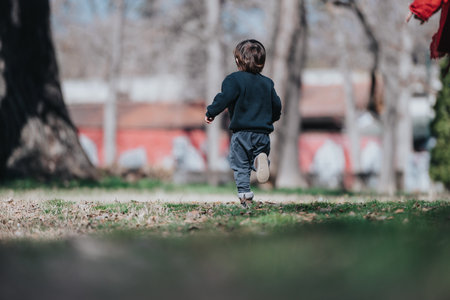 Small Child Running on Grass in a Park During a Bright Sunny Dayの写真素材