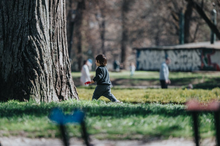 Young child running through a serene park on a sunny dayの写真素材