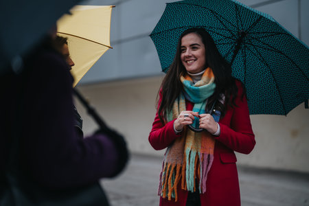 Women spending time together on a rainy city day with umbrellasの写真素材