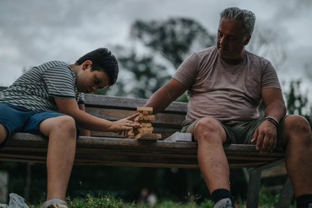 Father and son bonding over a game on a park benchの写真素材