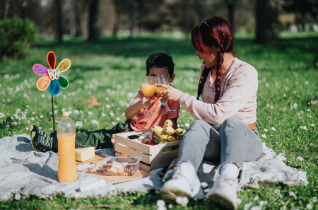 Mother and son enjoying a picnic with orange juice in a green parkの写真素材