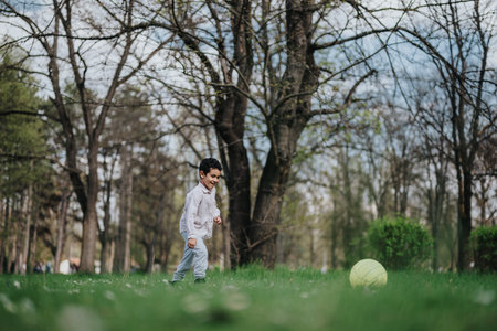 Young boy playing with a ball in a forest park settingの写真素材