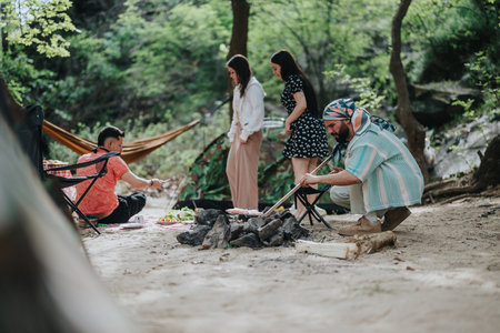 Friends enjoying a camping trip with a fire in a forest settingの写真素材