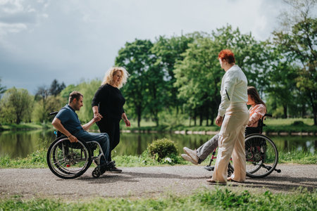 Group of individuals, including wheelchair users, enjoying a serene outdoor park setting during a sunny day with nature and companionship in focus.の写真素材