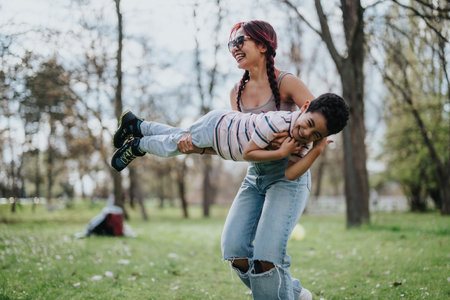 Mother playing outdoors with her happy son during a sunny day in the park.の写真素材