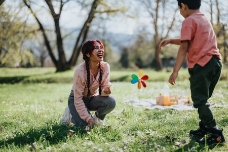 Mother and child enjoying a playful moment outdoors during a sunny picnic dayの写真素材