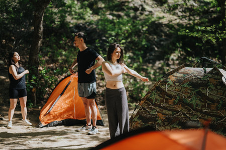 Group of friends stretching near camping tents in a forest settingの写真素材