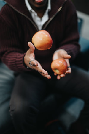 Person skillfully juggling fresh apples in a dynamic indoor settingの写真素材