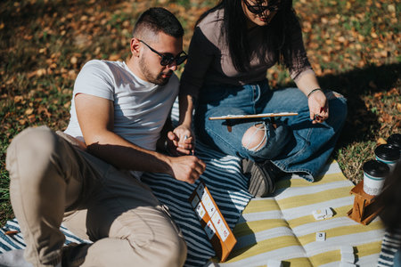 Young couple enjoying a relaxing outdoor picnic while playing board games on a sunny day in the park