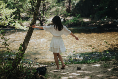 Young woman enjoying nature near a calm creek in the forestの写真素材