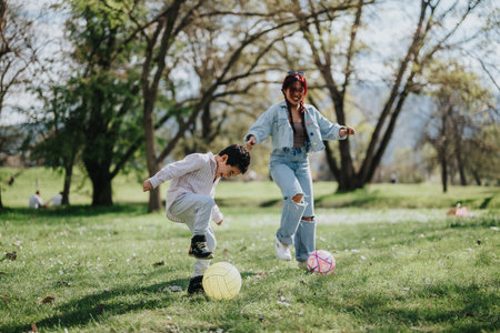 Mother and child enjoying a sunny day playing soccer in the parkの写真素材
