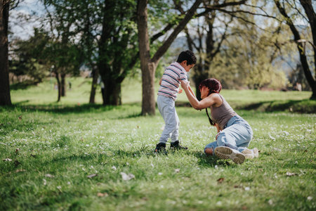 Asian mother supporting her child in a peaceful park settingの写真素材