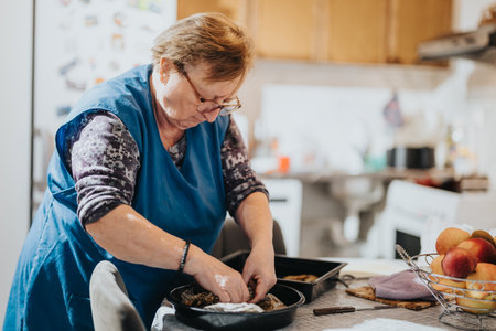 Elderly woman preparing food in a cozy kitchen, focusing intentlyの写真素材