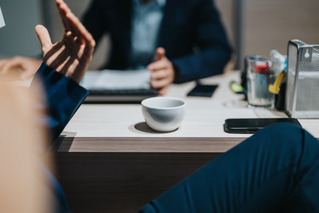 Colleagues discussing business topics over coffee in a professional office environmentの写真素材