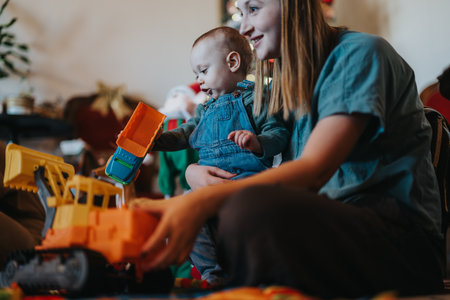 Mother and baby enjoying playtime with toy trucks in a cozy indoor settingの写真素材