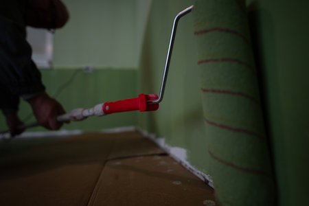 Close-up of a paint roller being used to apply green paint on a wall during a home improvement projectの写真素材