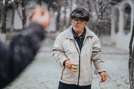 Senior man holding a mug in a snowy outdoor settingの写真素材