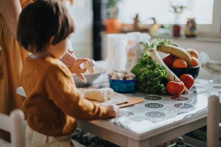 Mother and child preparing a healthy meal together at home, showcasing fresh ingredients and teamworkの写真素材