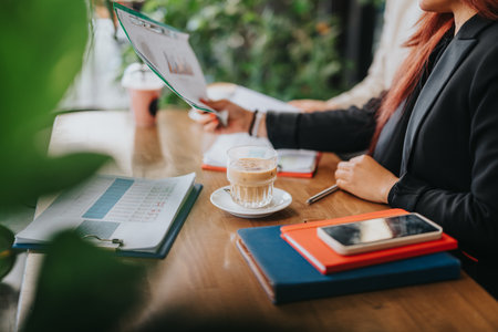 Colleagues Reviewing Business Documents Over Coffee During a Productive Meetingの写真素材
