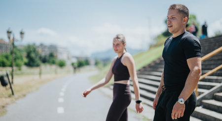 Two individuals in active wear walking outdoors near park and urban surroundings