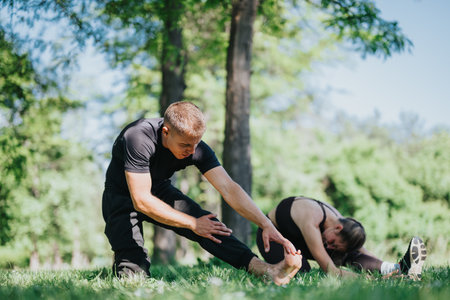 Two people stretching outdoors in a park on a sunny dayの写真素材