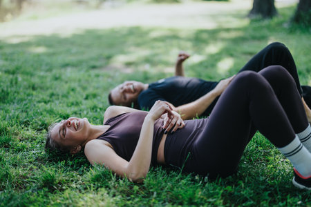 Couple relaxing after workout on grass in a sunny parkの写真素材