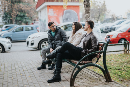 Three friends chatting on a park bench during a casual outdoor gatheringの写真素材