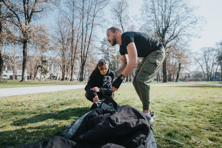 Two teenagers organizing outdoor activity equipment in a park with greenery and trees, emphasizing teamwork and preparation.の写真素材