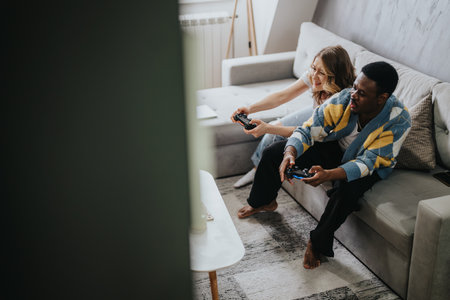 Smiling diverse couple enjoying video gaming together on a couch at home