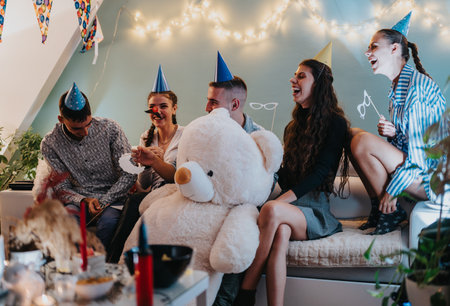 Group of friends laughing and enjoying a birthday celebration at home.の写真素材