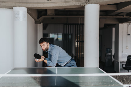 Businessman enjoying a break with table tennis in modern officeの写真素材