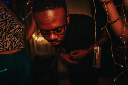 Friends enjoying a lively celebration with lights and joyful expressionsの写真素材