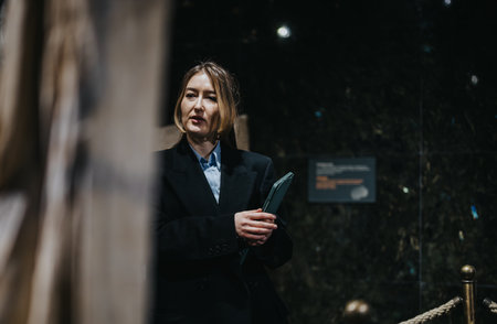 A woman in a museum observes an exhibit while holding a folder